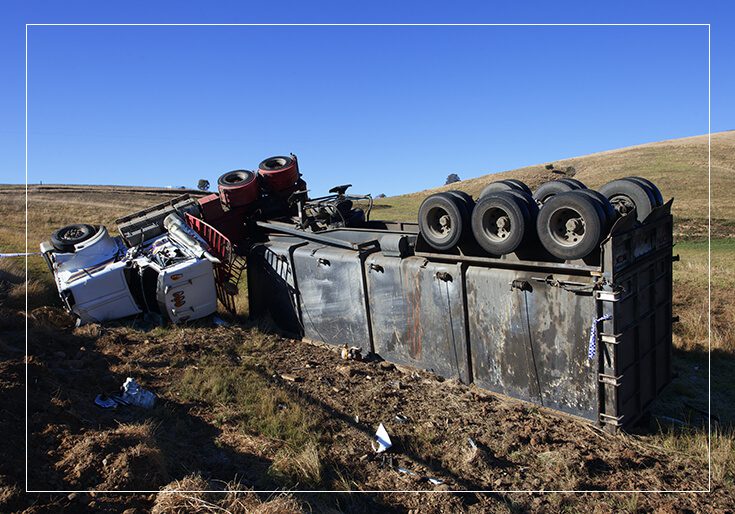 A truck that has been overturned in the grass.