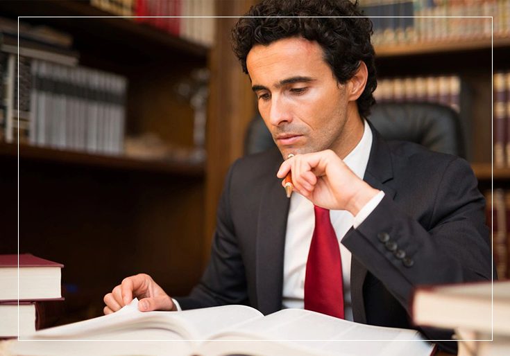 A man in suit and tie sitting at table with papers.