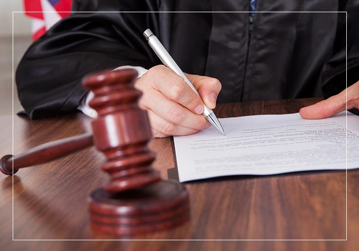 A person writing on paper next to a judge 's gavel.