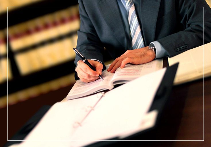 A man in suit writing on paper with pen.