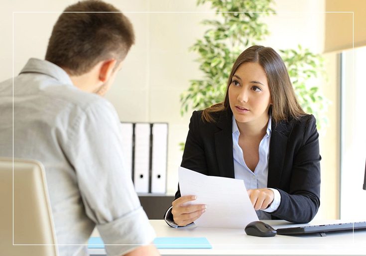 A woman is interviewing a man in an office.