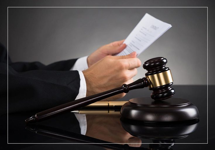 A person holding papers and a gavel on top of a table.