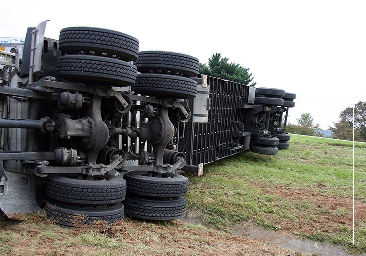 A truck that has been overturned on the side of the road.