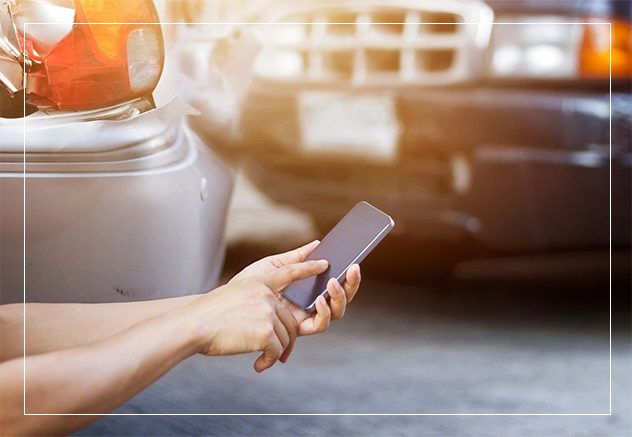 A person holding their cell phone in front of a car.