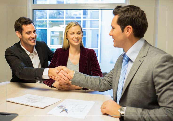 A man and woman shaking hands over papers.