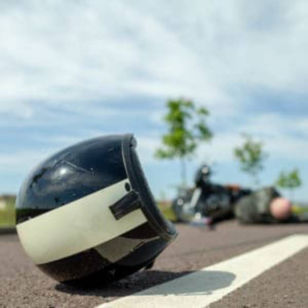 A motorcycle helmet laying on the ground in front of another motorcycle.