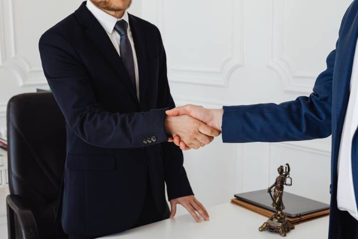 Two people shaking hands over a table.