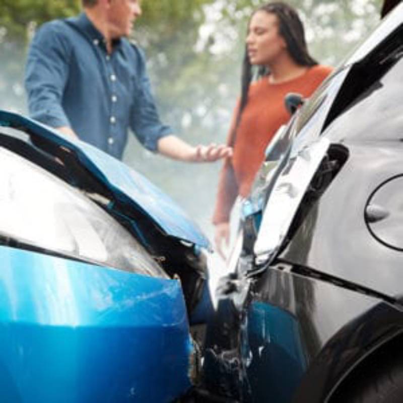 Two people shaking hands over a car accident.